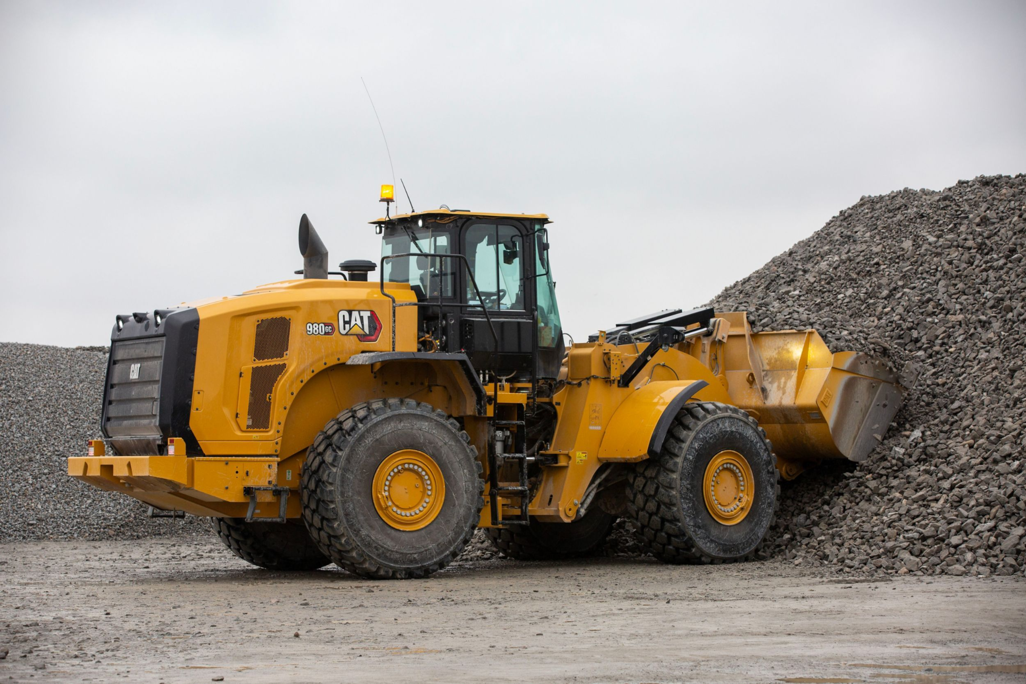 Large yellow wheel loader beside a pile of crushed rock