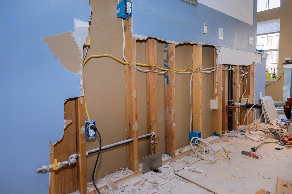 Interior wall opened up to the studs with wiring and pipes exposed