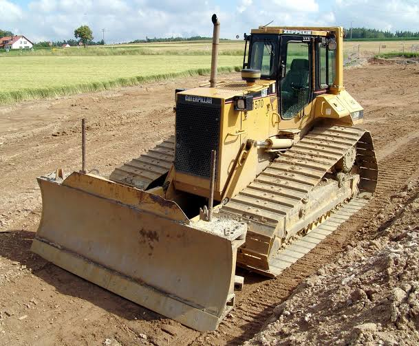 Yellow bulldozer with a wide blade on a graded dirt site